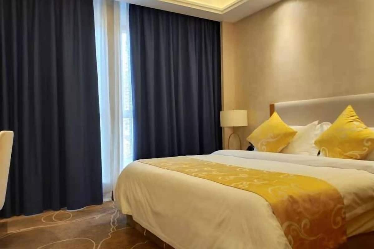 Habitación de hotel con cama, cortinas y lámpara.