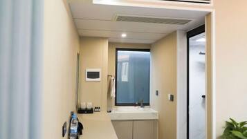 Un baño moderno con lavamanos, espejo y una ventana pequeña.