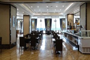 Un restaurant spacieux, doté de nombreuses tables et chaises, d’un bar et de grandes fenêtres qui laissent entrer la lumière naturelle.
