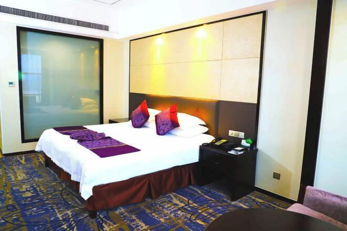 Une chambre d’hôtel comprenant un lit, une table de chevet, une chaise et une cloison en verre.