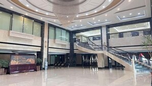 Een ruime lobby met een weelderige kroonluchter, een centrale trap en een groot receptiebalie.