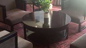 Mesa redonda com um vaso de plantas verdes, rodeada por quatro cadeiras com assentos acolchoados.
