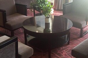 Een ronde tafel met een vaas groene planten, omringd door vier stoelen met zachte kussens.