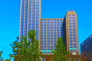 A high-rise building with a distinctive L-shaped structure, large windows, and a clear blue sky in the background. - Yantai Baohua Mingdu Hotel (Qixia)