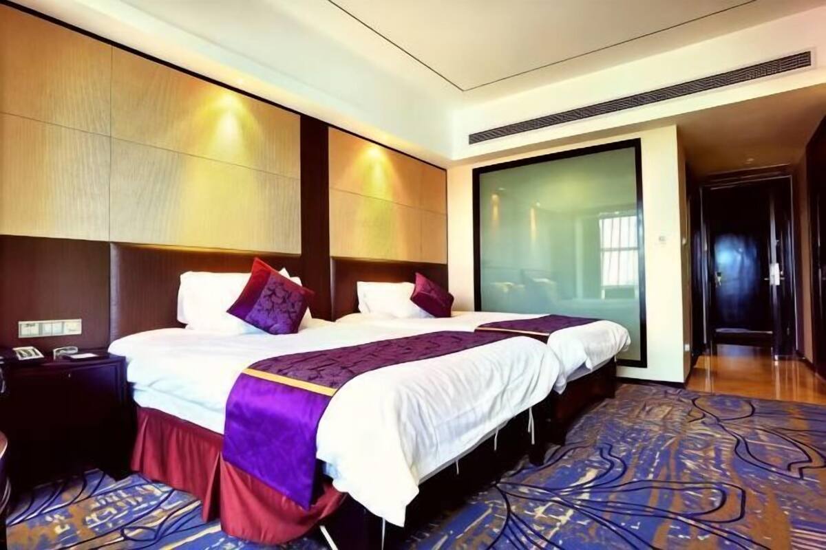 Une chambre d’hôtel avec deux lits, une table de chevet, un bureau et une grande fenêtre.