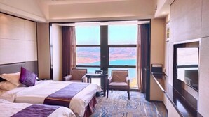Een hotelkamer met twee bedden, een bureau en uitzicht op een schilderachtig landschap.