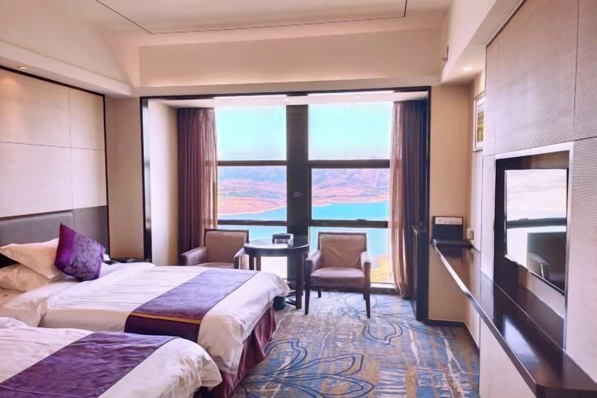 Une chambre d’hôtel avec deux lits, un bureau et une vue sur un paysage pittoresque.