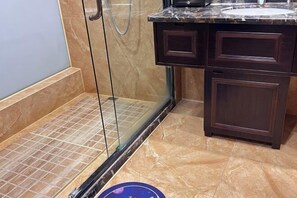 A bathroom with a glass shower enclosure, a marble countertop, and dark wooden cabinets. - Yantai Baohua Mingdu Hotel (Qixia)