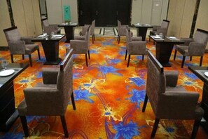 Une salle de conférence dotée d’un tapis à motifs floraux, de tables et de chaises disposées pour les réunions.