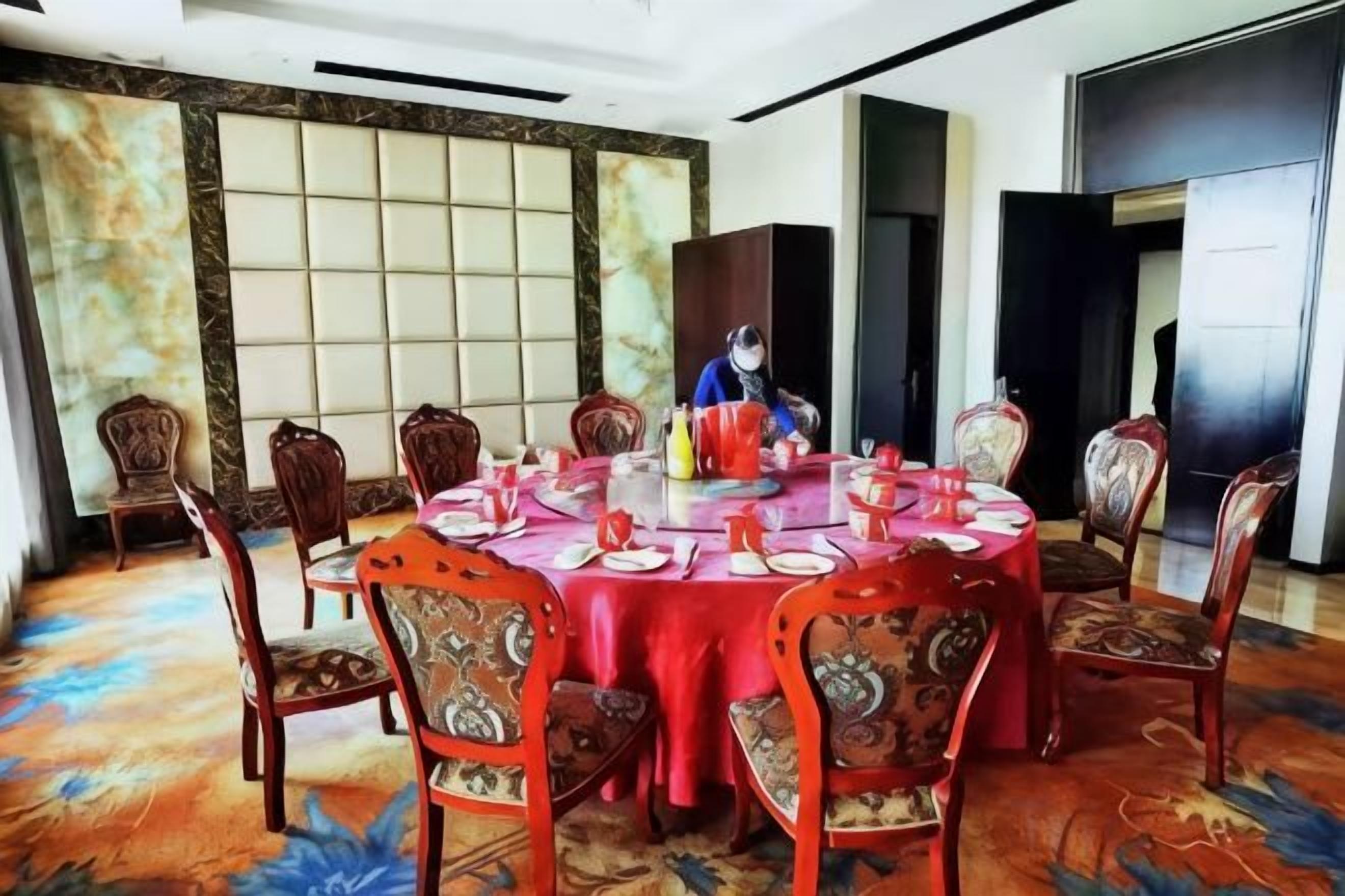 Un salón de conferencias con una mesa redonda, sillas y una persona sentada a la mesa.