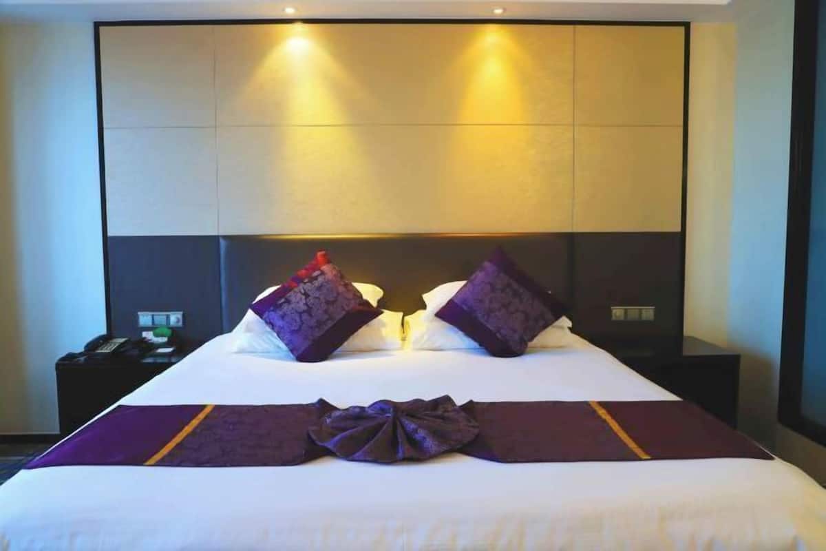 Une chambre d’hôtel avec un grand lit, deux tables de chevet, un téléphone et une lampe.