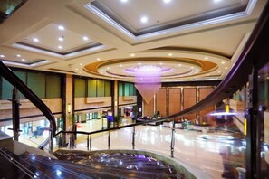 Un espace intérieur doté d’un escalier en colimaçon, d’un lustre central et d’un plancher poli.