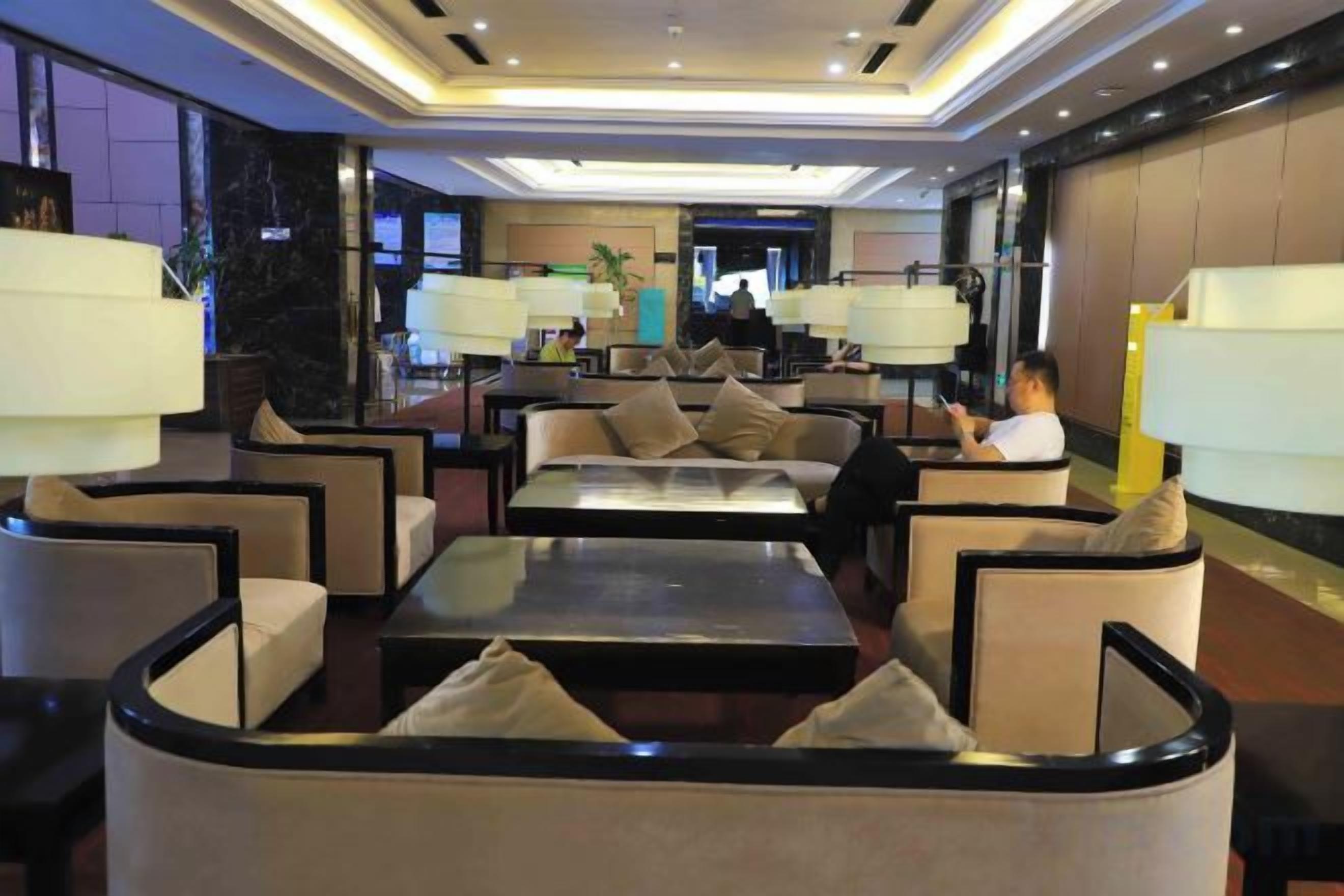 A hotel lobby with seating areas, a reception desk, and a large window.