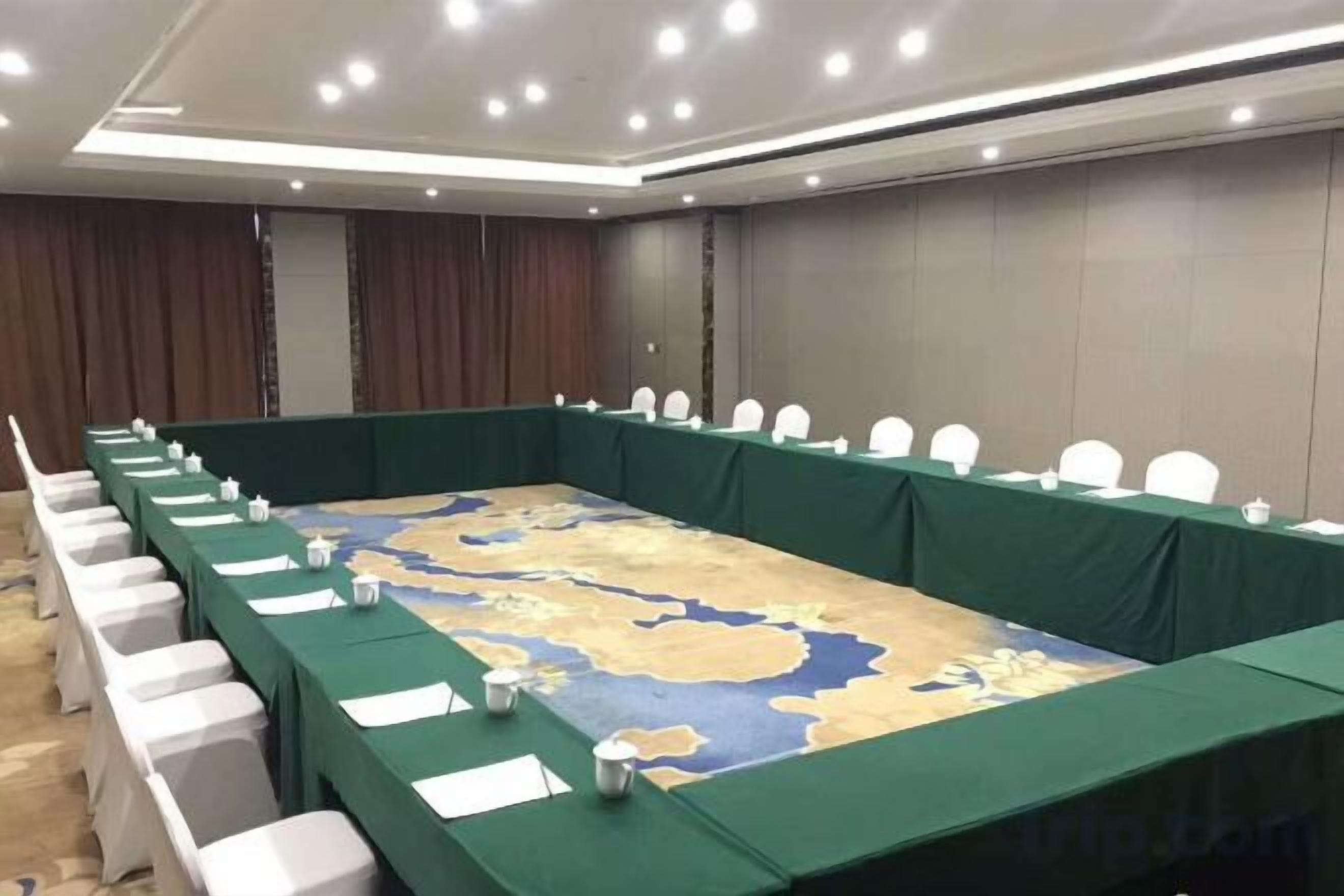 A conference room with a long table, white chairs, and a map on the table.