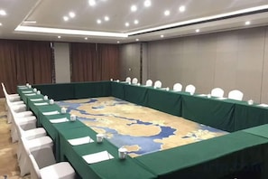 A conference room with a long table, white chairs, and a map on the table. - Yantai Baohua Mingdu Hotel (Qixia)