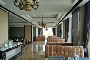 A spacious hotel lobby with a marble reception desk, plush seating, and a chandelier.