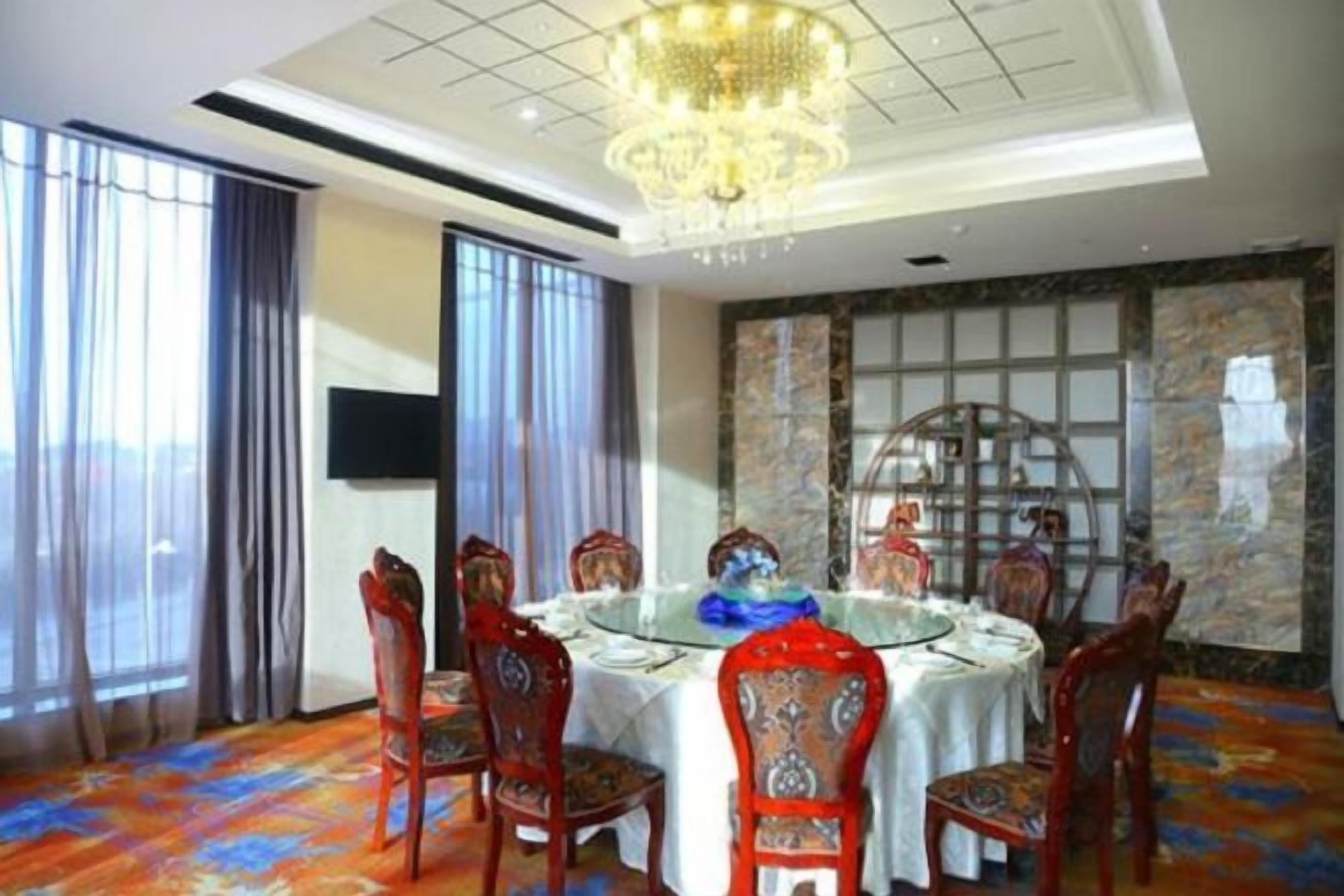 A dining area with a round table, chairs, and a chandelier.
