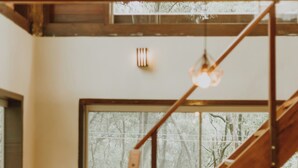 Eine Holztreppe mit Metallgeländer, ein Bücherregal aus Holz und ein großes Fenster mit Blick auf Bäume.