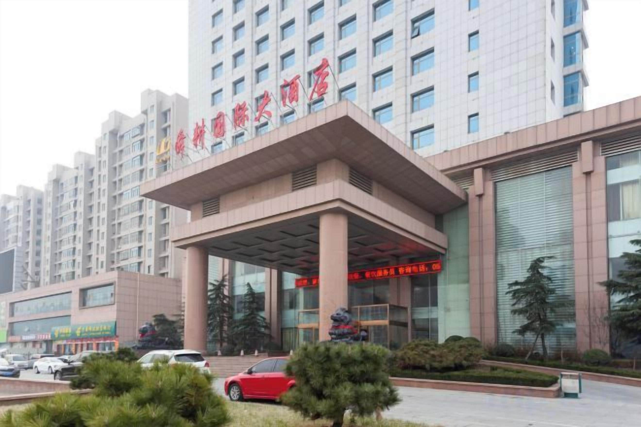 A hotel entrance with a covered walkway, multiple floors, and a signboard.
