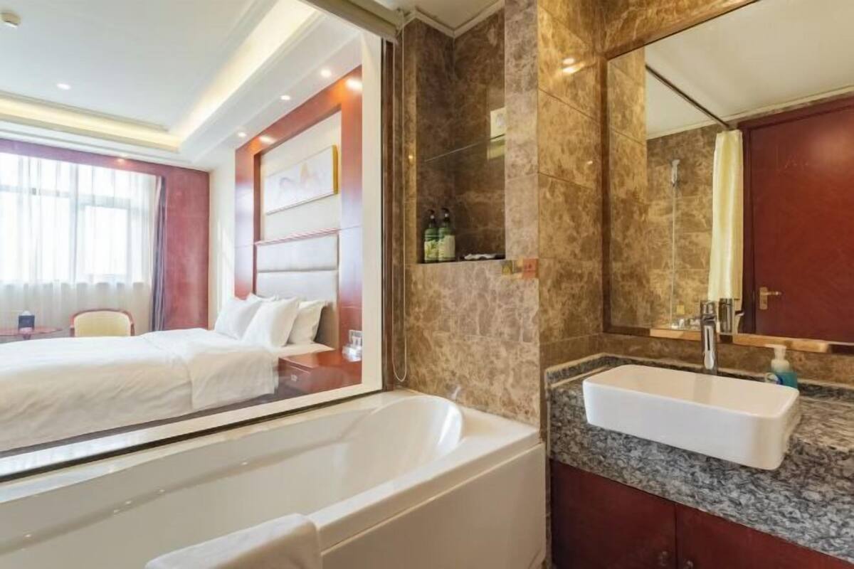 A hotel room with a large bathtub, a marble bathroom vanity, and a large mirror.