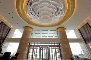 Een ruime lobby met een grote kroonluchter, hoge zuilen en een moderne entree.
