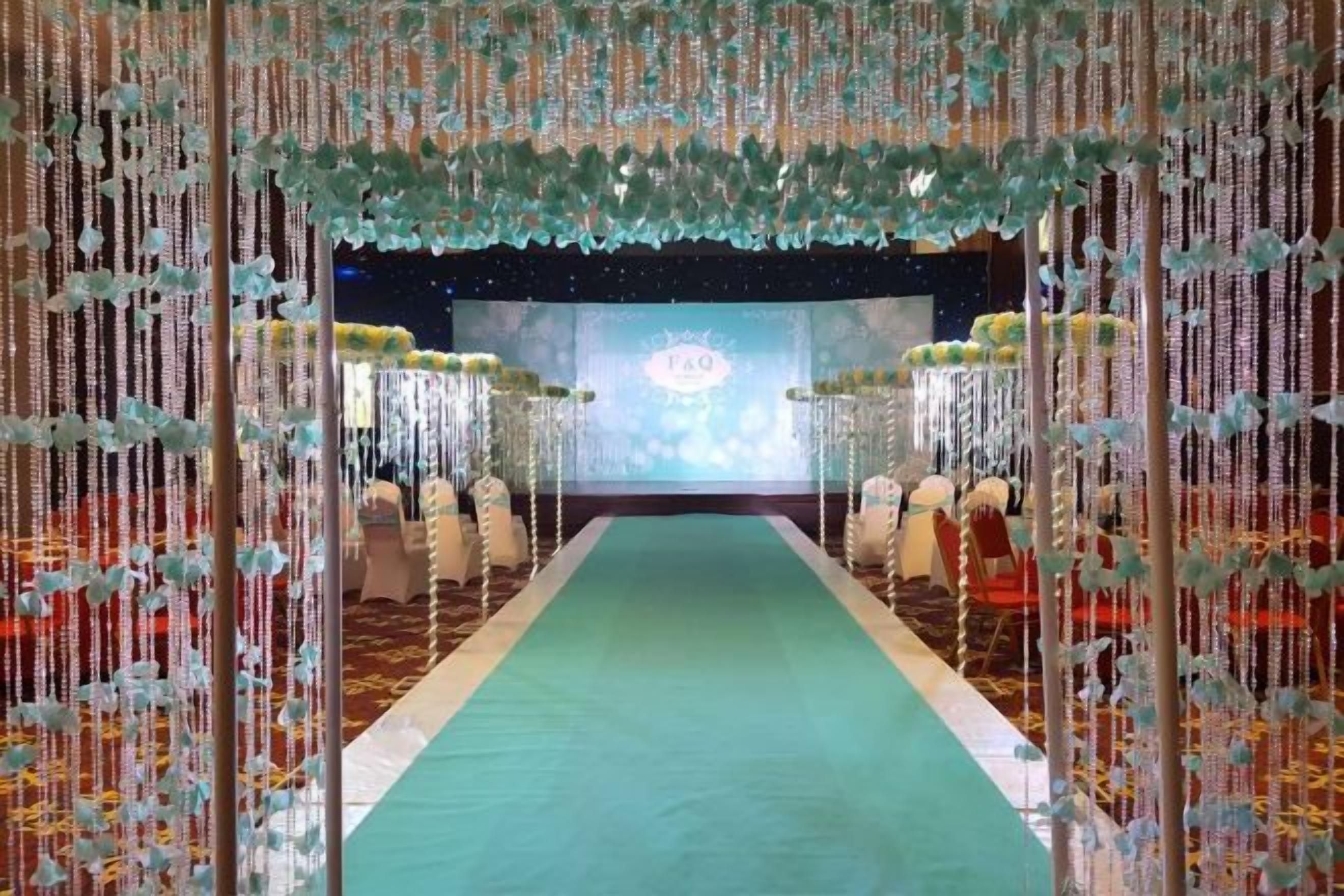A stage with a green carpet and a backdrop, surrounded by chairs.