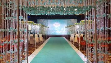 A stage with a green carpet and a backdrop, surrounded by chairs.