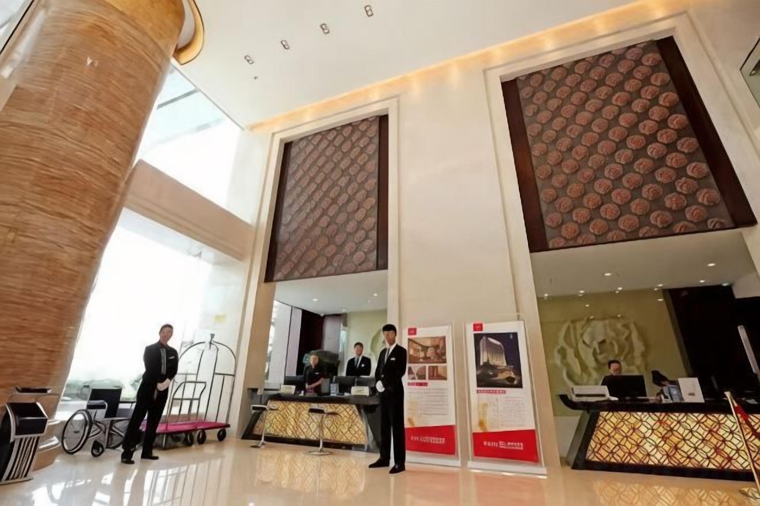 A hotel reception area with a modern design, including a reception desk, a counter, and a large pillar.