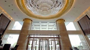 Un vestíbulo espacioso con una lámpara circular central, ventanas amplias y un diseño arquitectónico moderno.