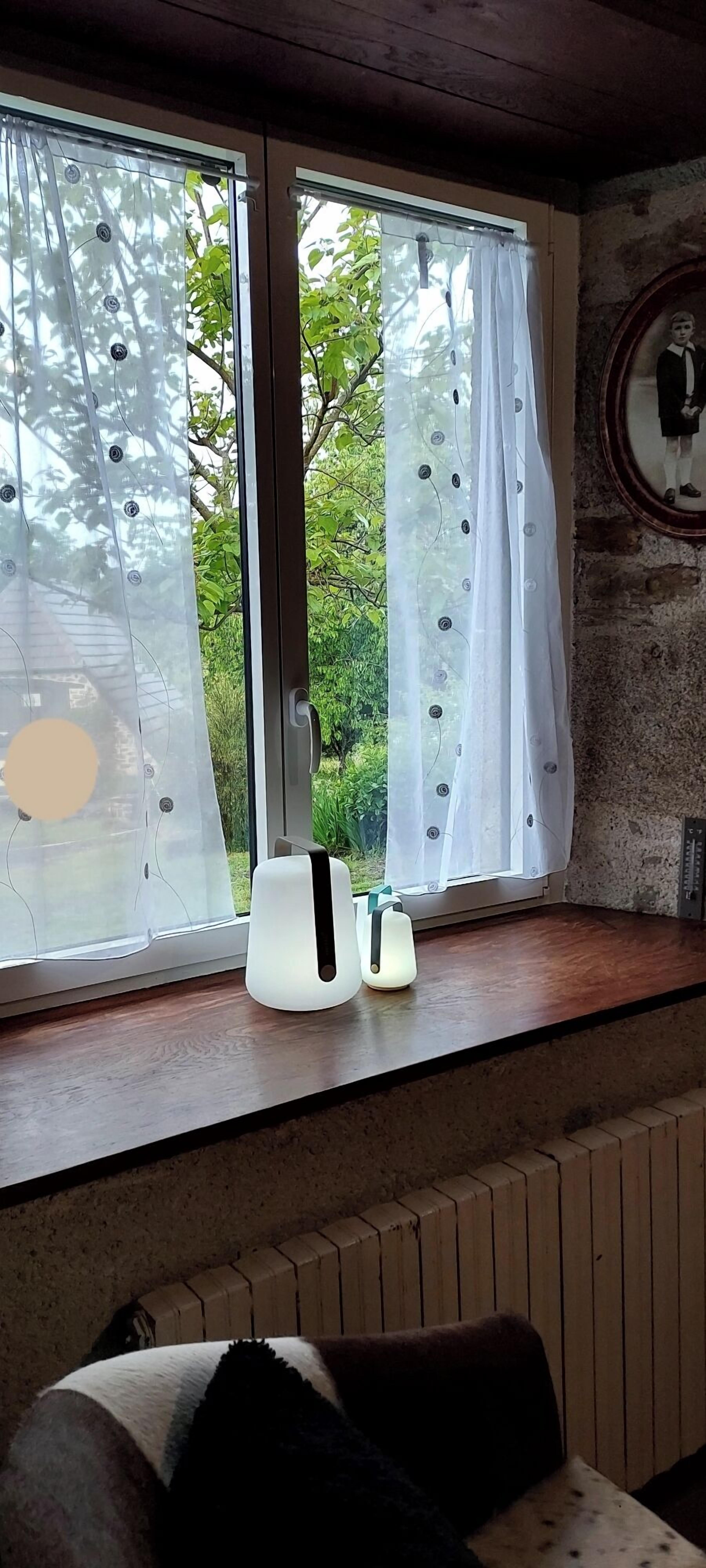 Une pièce avec une grande fenêtre, un radiateur en dessous et un miroir au mur.