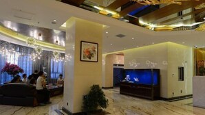 Eine geräumige Lobby mit Marmorböden, einer Rezeption, einem großen Aquarium und einer modernen Chandelier.