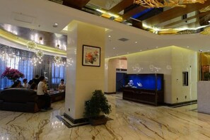 A lobby with a reception desk, seating area, and a TV screen.