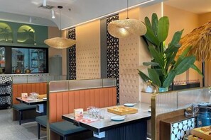 Interior de restaurante con cabinas, barra y luces colgantes.
