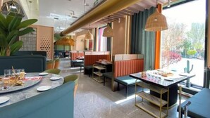 Ein modernes Restaurantambiente mit Sitzecken, Tischen und hängenden Pendelleuchten.