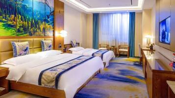 A hotel room with two beds, a large painting, a TV, and a desk with a lamp.