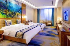 Habitación de hotel con dos camas, un cuadro grande, un televisor y un escritorio con lámpara.