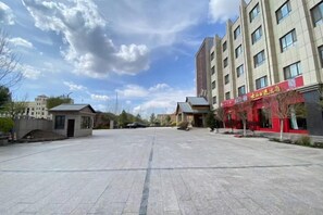 Un patio amplio con un edificio que tiene un escaparate rojo a la derecha.