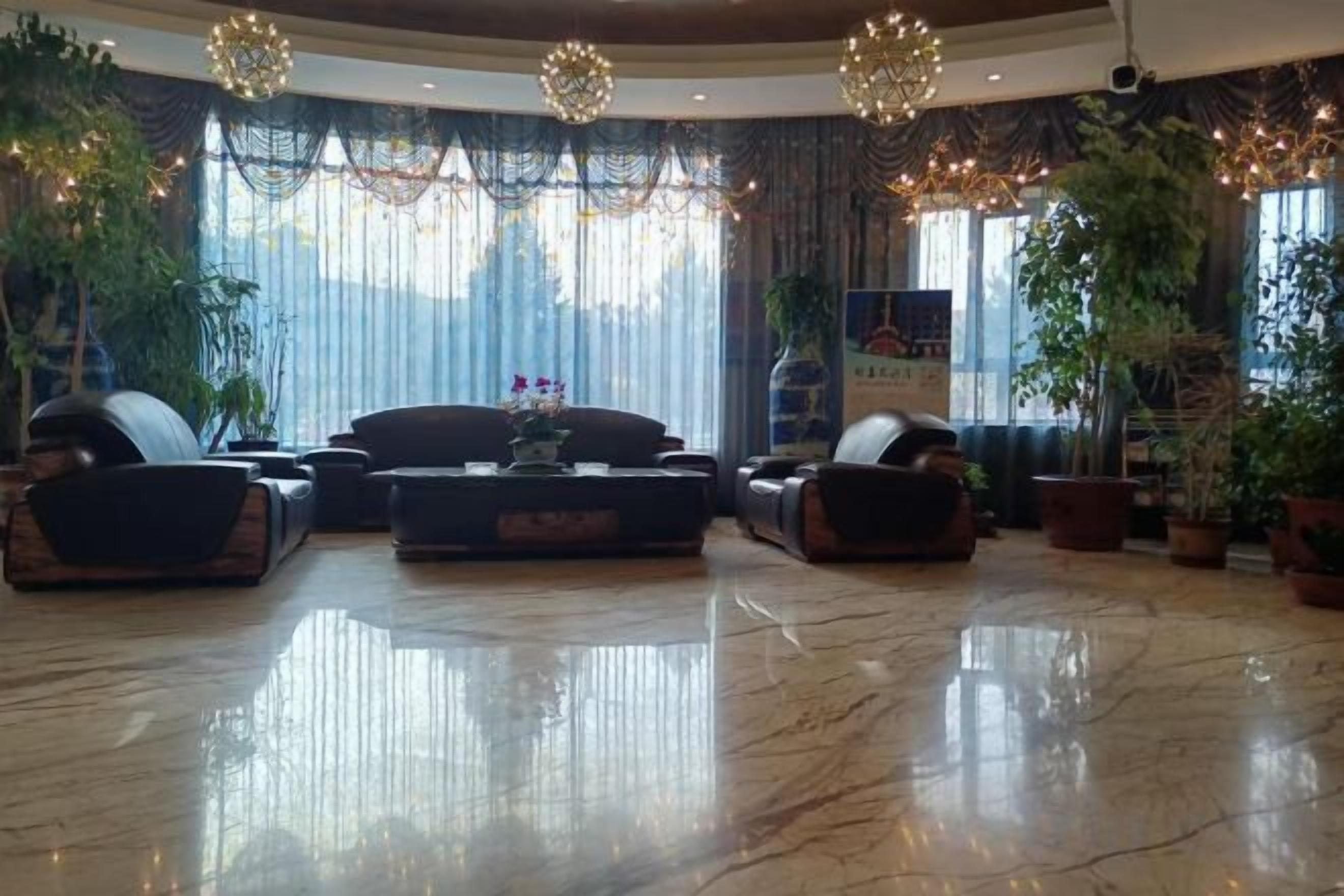 A spacious lobby with a marble floor, a sofa set, and potted plants.