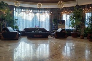 Un hall d’entrée spacieux, doté d’un sol en marbre, d’un ensemble de canapés et de plantes en pot.