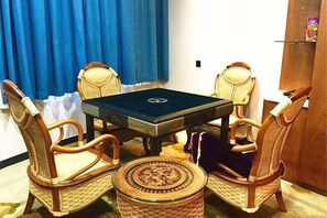 A dining area with a table and four chairs, a small round table, and a blue curtain in the background.