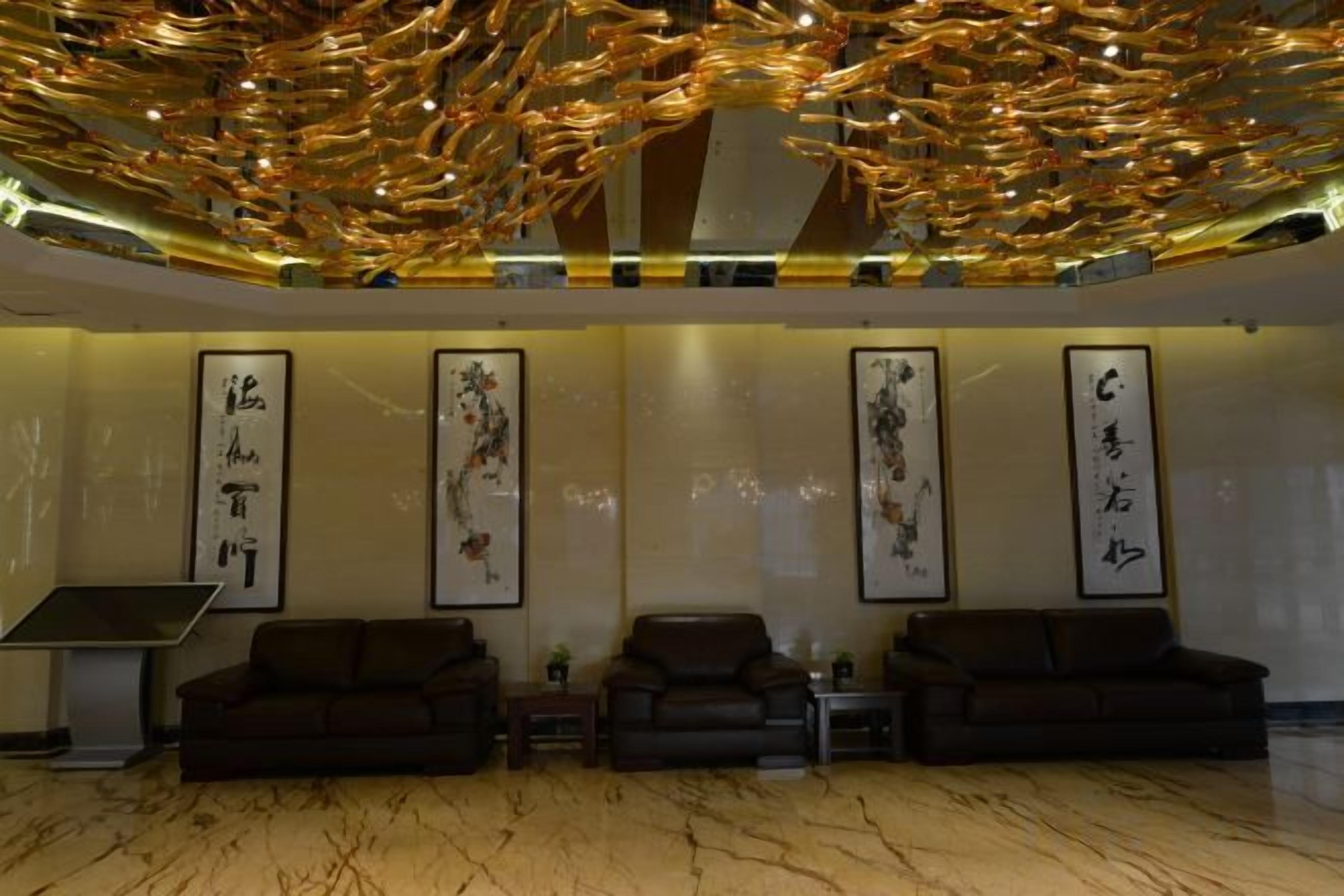A lobby with a high ceiling, a marble floor, and four framed calligraphy pieces on the wall.