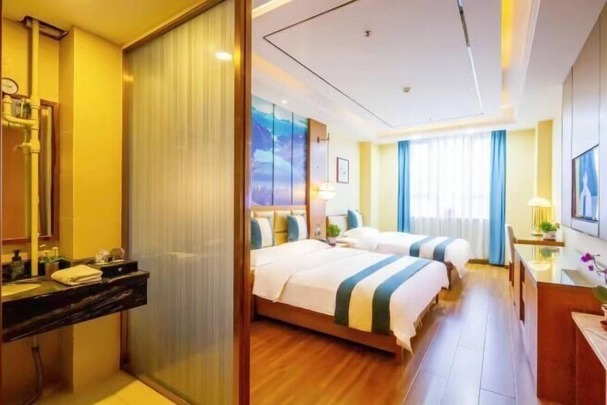 Habitación de hotel con cama, mesita de noche y vista al exterior.