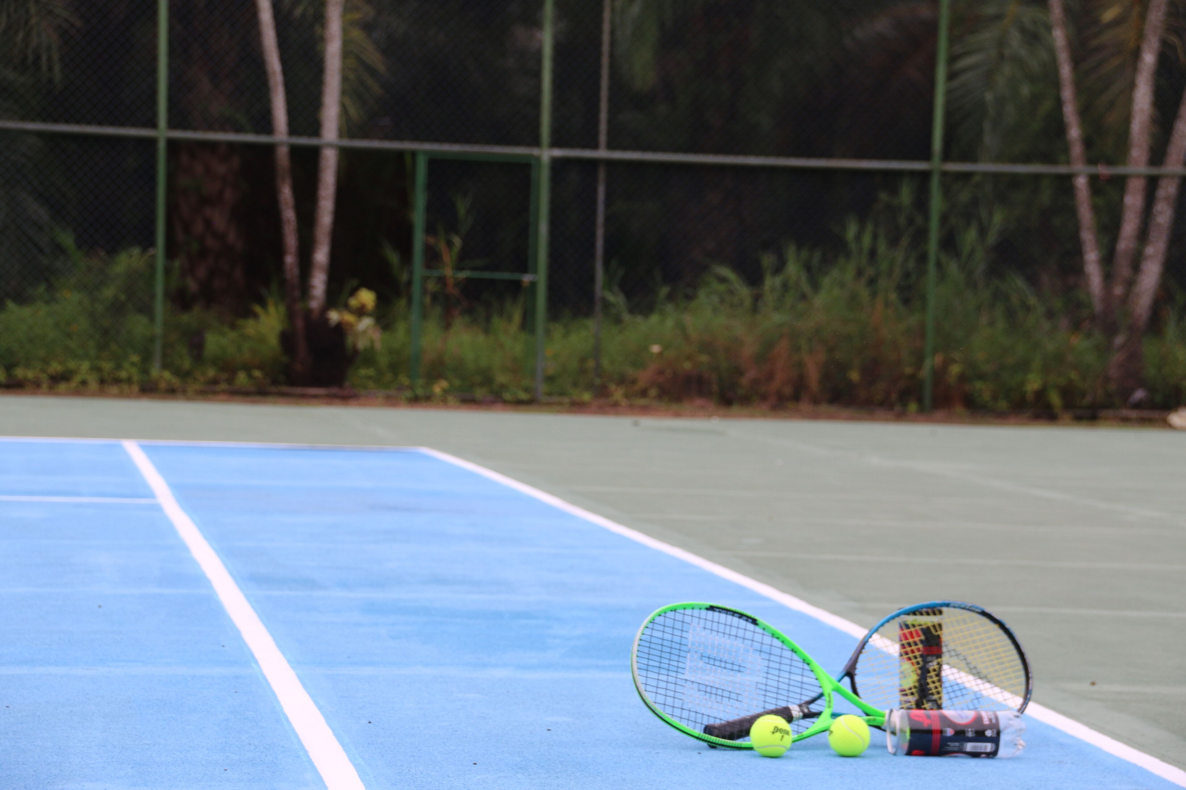 Un court de tennis avec deux raquettes de tennis, une balle de tennis et une canette de boisson énergisante.