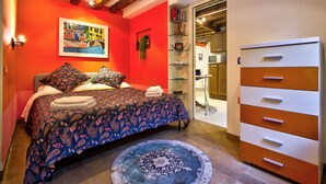 A bedroom with a bed, a dresser, and a painting on the wall. - Biennial-Pulse (Venezia)