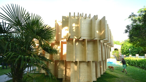 A wooden structure with a unique design, surrounded by greenery. - Biennial-Pulse (Venezia)