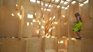 A wooden interior with a high ceiling and skylights, featuring a person standing on a platform. - Biennial-Pulse (Venezia)