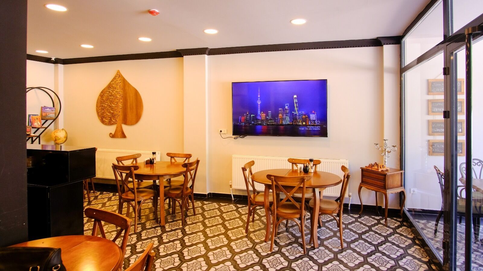 A dining area with two round tables, wooden chairs, a globe, and a chessboard.