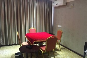 A hotel room with a dining table, four chairs, a small round table, and a trash bin. - Xin Haiyi Hotel (Kaiping)