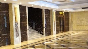 A spacious lobby with marble flooring, a staircase, and a reception area with a sign. - Xin Haiyi Hotel (Kaiping)