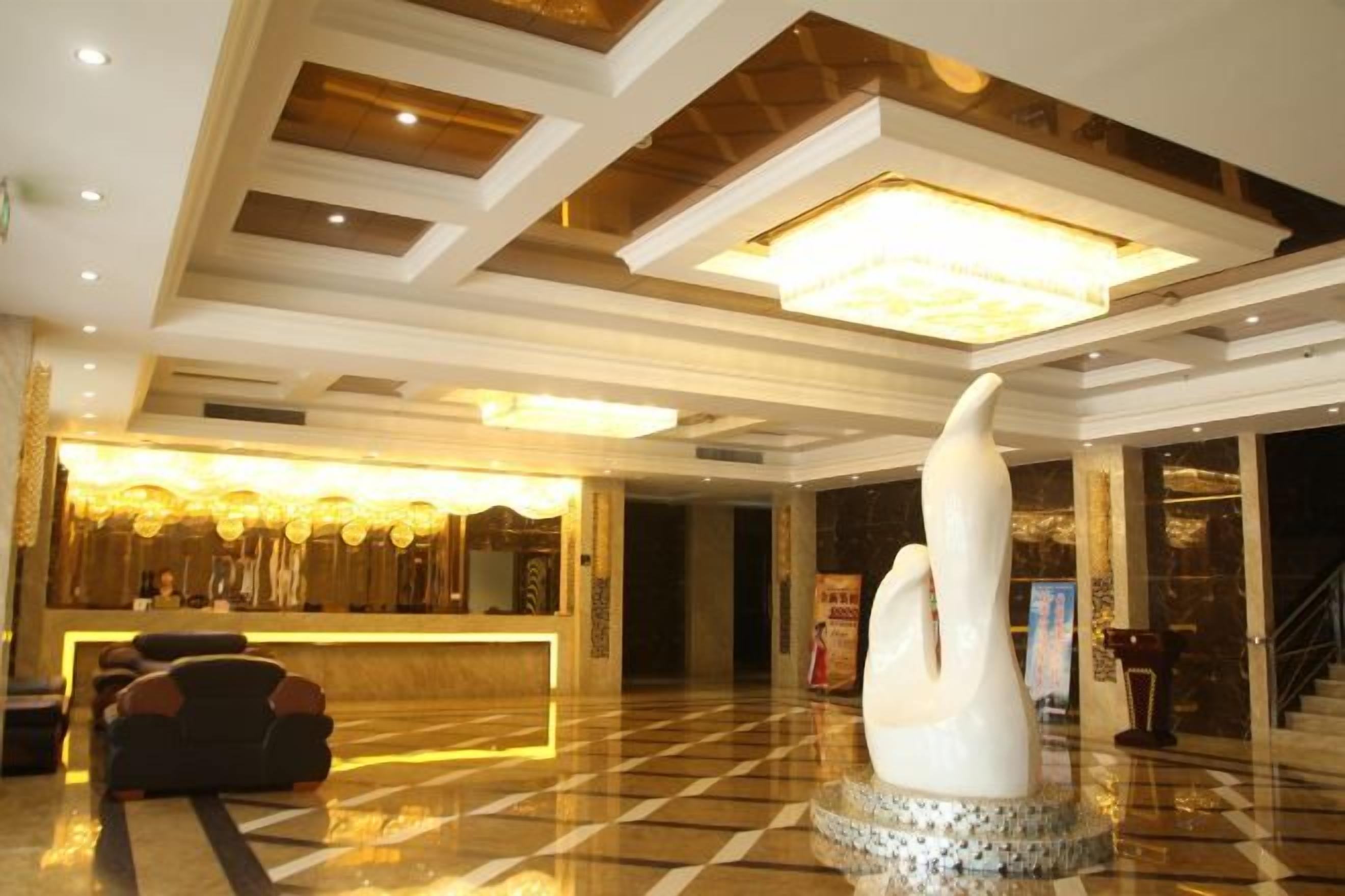 Eine Hotelhalle mit einer Rezeption, einer großen weißen Skulptur und einem Check-in-Schalter.